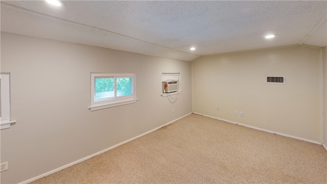 carpeted empty room with a textured ceiling, cooling unit, and vaulted ceiling