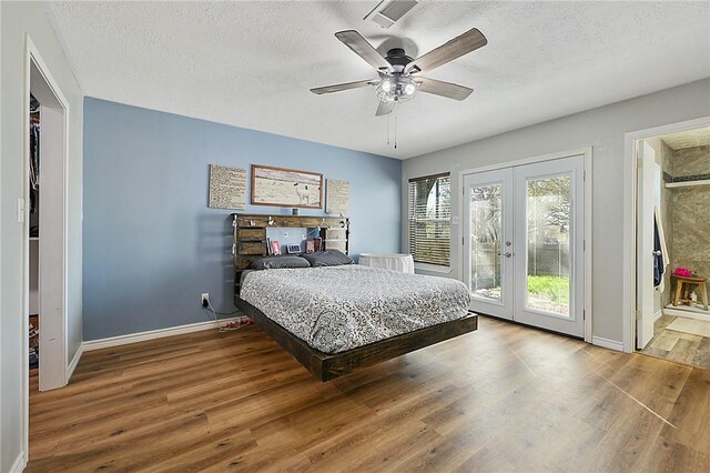 bedroom with ceiling fan, french doors, wood-type flooring, and a textured ceiling