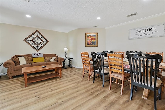 dining area with light wood-type flooring and a textured ceiling