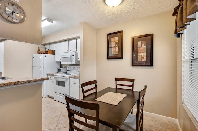 dining area featuring a textured ceiling, baseboards, and light tile patterned floors