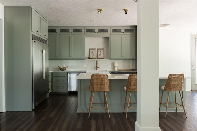 1107 Royal Adelade Dr, College Station, TX 77845 - kitchen with a sink, light countertops, a kitchen breakfast bar, dark wood finished floors, and stainless steel appliances