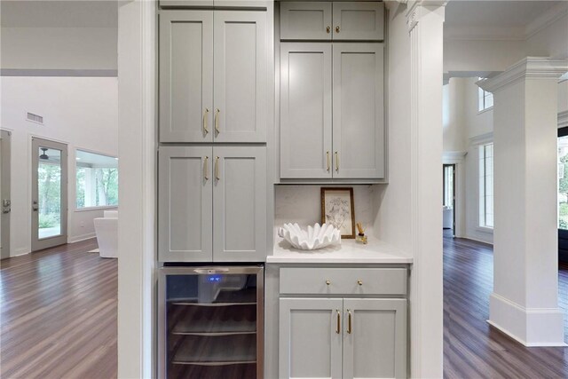 1107 Royal Adelade Dr, College Station, TX 77845 - bar area featuring wine cooler, dark wood-type flooring, decorative columns, crown molding, and a towering ceiling