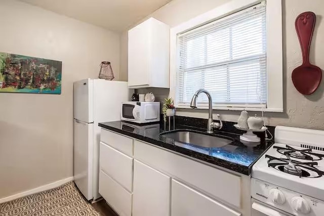 1017 Milner Dr, College Station, TX 77840 - kitchen with white appliances, a sink, white cabinetry, and dark stone countertops