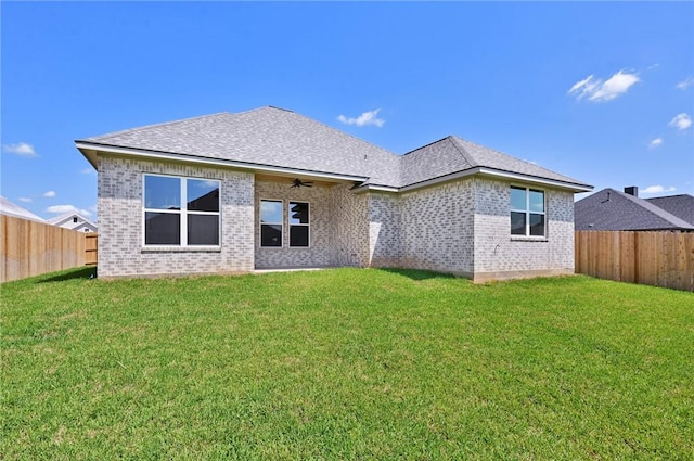 rear view of property featuring ceiling fan and a yard