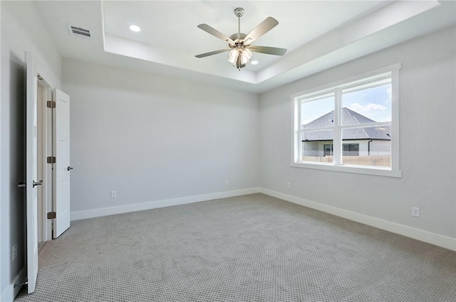 carpeted empty room with a tray ceiling and ceiling fan