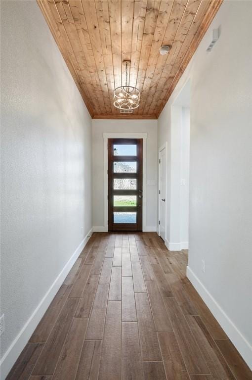 doorway with ornamental molding, dark wood-type flooring, a chandelier, and wood ceiling