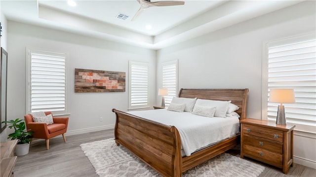 bedroom featuring recessed lighting, a tray ceiling, visible vents, a ceiling fan, and light wood-type flooring