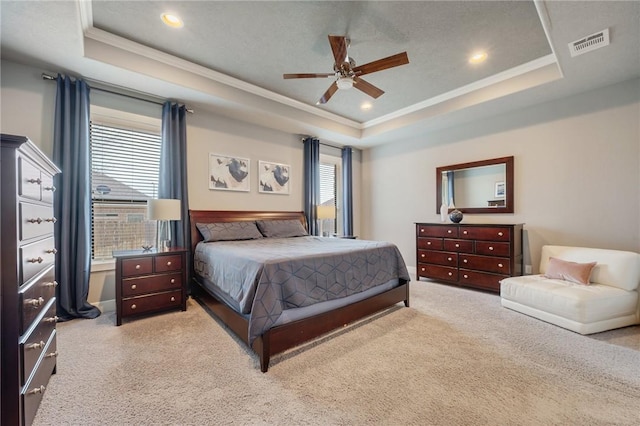 bedroom with visible vents, light carpet, crown molding, a raised ceiling, and ceiling fan