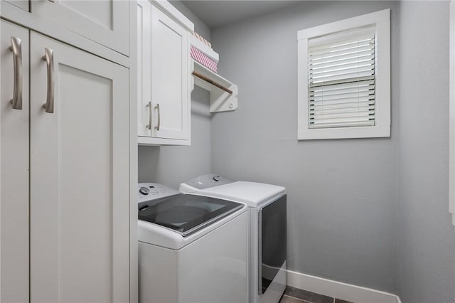 washroom featuring cabinet space, baseboards, and washing machine and clothes dryer