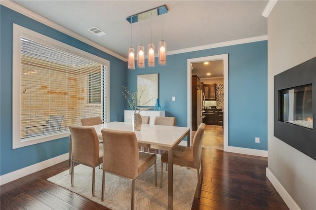 dining area with visible vents, baseboards, dark wood finished floors, and crown molding