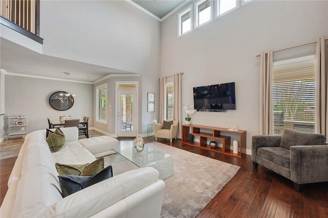 living area featuring baseboards, wood finished floors, a towering ceiling, and ornamental molding