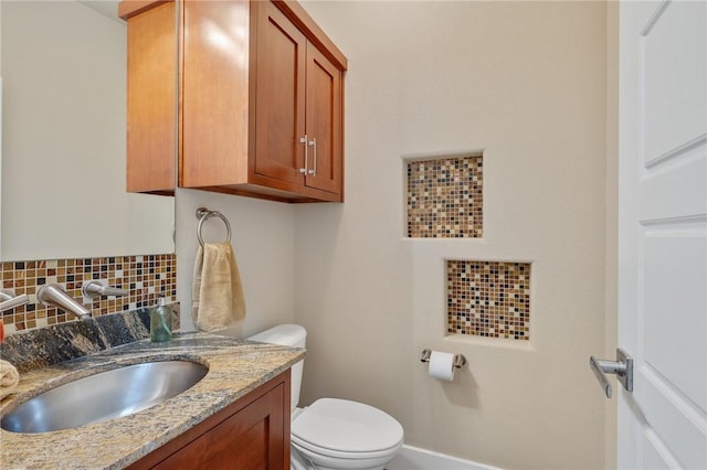 bathroom featuring decorative backsplash, toilet, vanity, and baseboards