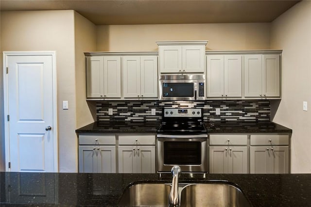 kitchen with stainless steel appliances, sink, dark stone countertops, and backsplash