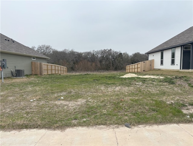 view of yard with central AC and fence