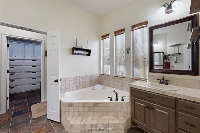 7576 River Ridge Drive, College Station, TX 77845 - bathroom featuring vanity, a garden tub, and stone tile flooring