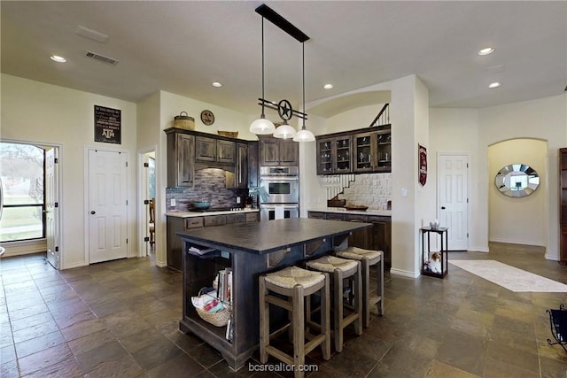 7576 River Ridge Drive, College Station, TX 77845 - kitchen with stainless steel double oven, dark brown cabinetry, backsplash, a kitchen island, and recessed lighting