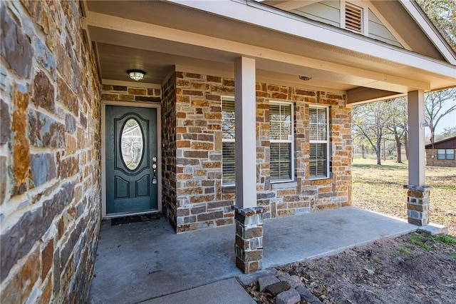 view of exterior entry with stone siding and a porch