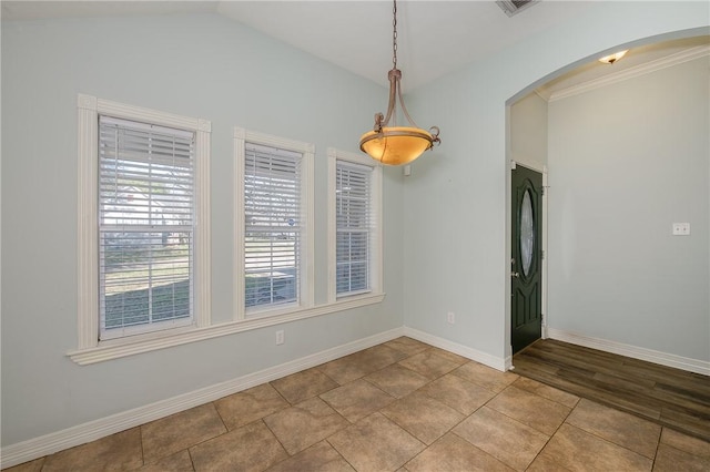 unfurnished dining area with arched walkways, visible vents, lofted ceiling, and baseboards