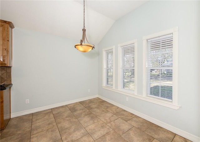 unfurnished dining area with vaulted ceiling, baseboards, and tile patterned floors