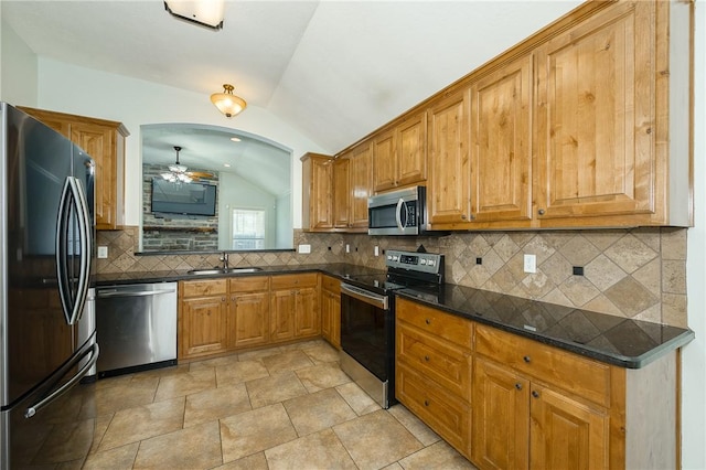 kitchen with stainless steel appliances, lofted ceiling, a sink, and dark countertops