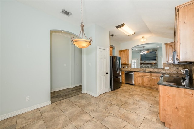 kitchen with arched walkways, stainless steel appliances, dark countertops, visible vents, and a sink