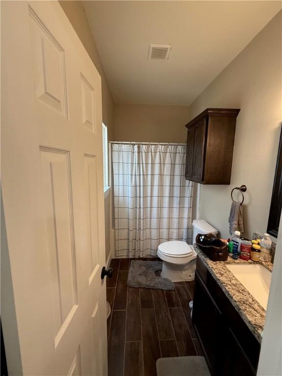 4004 Oaklawn St, Bryan, TX 77801 - full bathroom featuring vanity, toilet, wood finish floors, and curtained shower