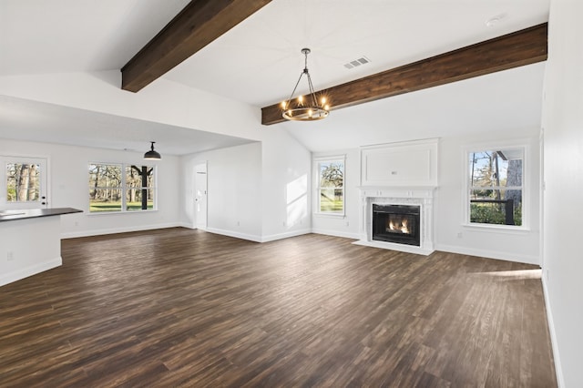 unfurnished living room with dark hardwood / wood-style flooring, lofted ceiling with beams, an inviting chandelier, and a healthy amount of sunlight