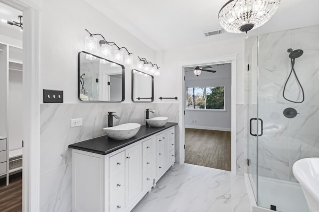 bathroom featuring tile walls, vanity, a shower with shower door, and ceiling fan with notable chandelier