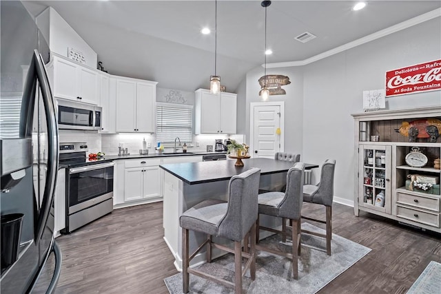kitchen with a breakfast bar area, dark wood-style flooring, stainless steel appliances, a sink, and visible vents