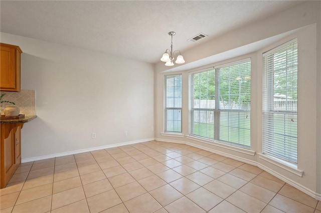 unfurnished dining area with a chandelier, baseboards, light tile patterned floors, and visible vents
