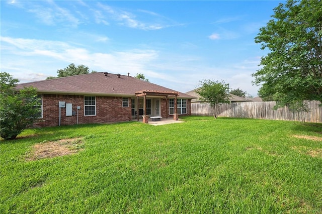 back of property with brick siding, fence, a lawn, and a patio