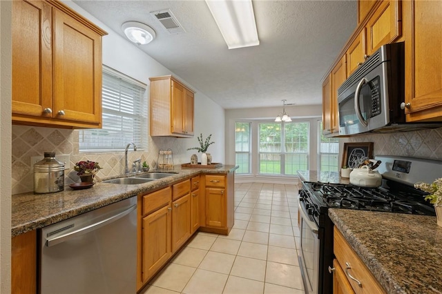 kitchen with a sink, stainless steel appliances, light tile patterned flooring, visible vents, and decorative backsplash