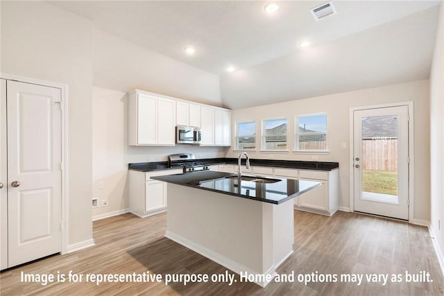 kitchen with white cabinetry, stainless steel appliances, lofted ceiling, and light wood-type flooring