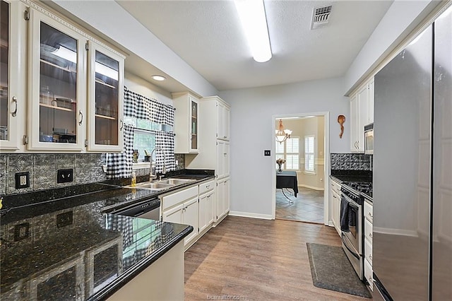 kitchen with appliances with stainless steel finishes, light wood-type flooring, sink, a notable chandelier, and white cabinets