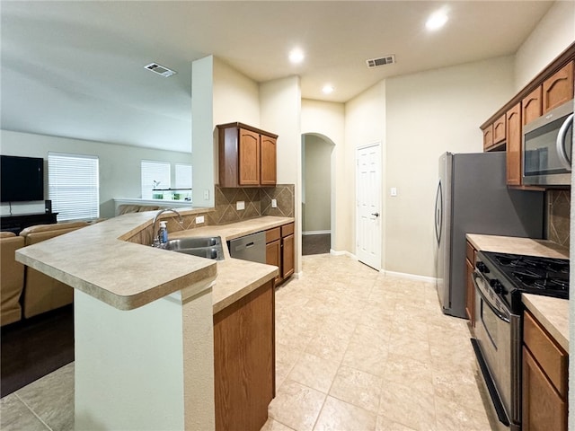 kitchen with sink, a kitchen breakfast bar, backsplash, kitchen peninsula, and appliances with stainless steel finishes