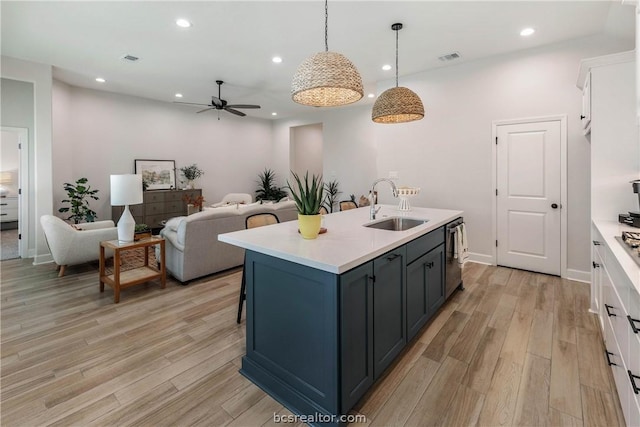 kitchen featuring white cabinets, pendant lighting, sink, and light hardwood / wood-style flooring