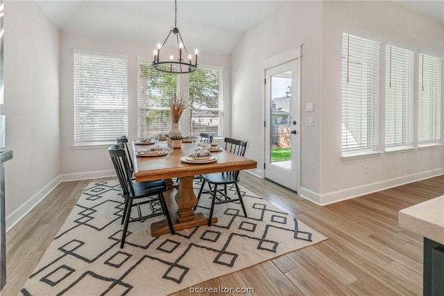 dining area featuring a chandelier, light hardwood / wood-style floors, and lofted ceiling