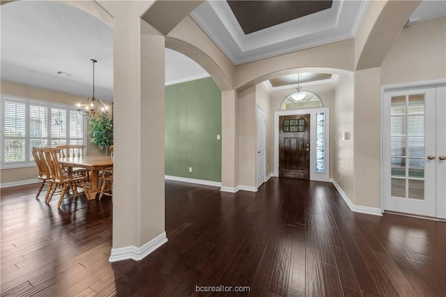 foyer entrance featuring crown molding, dark wood-type flooring, and a notable chandelier