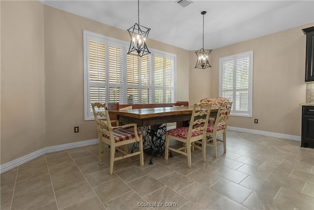 tiled dining space featuring a healthy amount of sunlight and an inviting chandelier