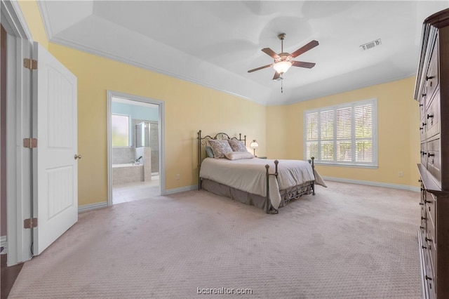 carpeted bedroom featuring ceiling fan, ornamental molding, a tray ceiling, and ensuite bath