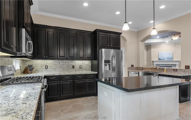 kitchen with decorative light fixtures, a center island, stainless steel appliances, and ornamental molding