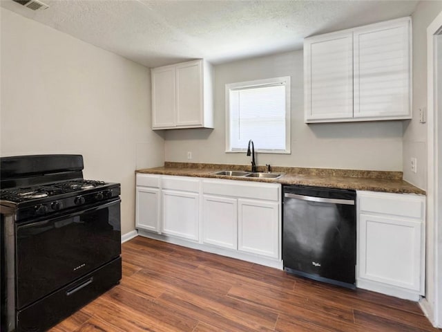 kitchen featuring white cabinetry, a sink, dark countertops, dishwasher, and gas stove