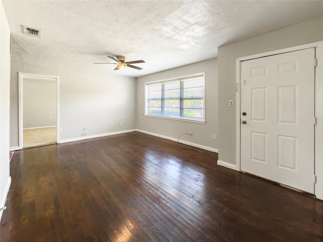 interior space featuring a textured ceiling, visible vents, baseboards, dark wood finished floors, and a ceiling fan