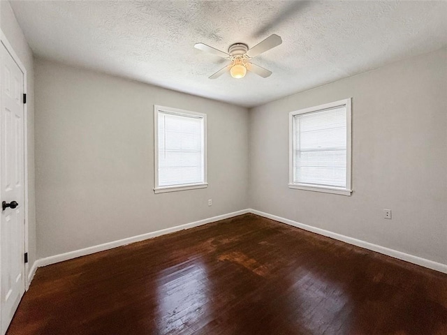 unfurnished room with a textured ceiling, a ceiling fan, dark wood finished floors, and baseboards