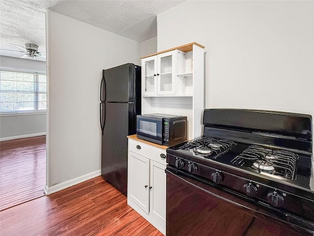 kitchen featuring white cabinets, black appliances, dark wood-style flooring, baseboards, and a textured ceiling