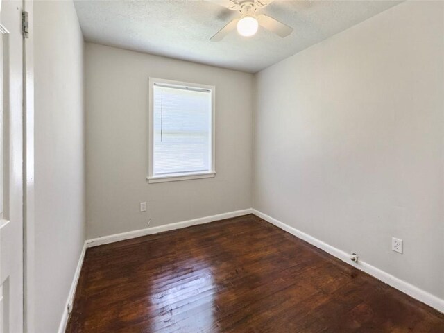 empty room with baseboards, a ceiling fan, and dark wood-style floors