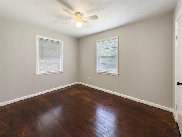 unfurnished room featuring baseboards, a ceiling fan, and dark wood-type flooring