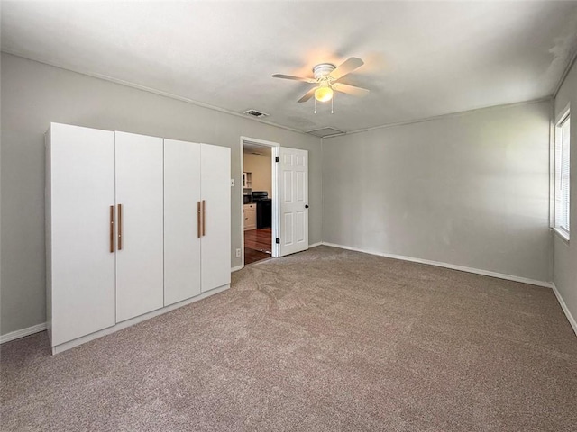 unfurnished bedroom featuring baseboards, visible vents, a ceiling fan, and carpet flooring