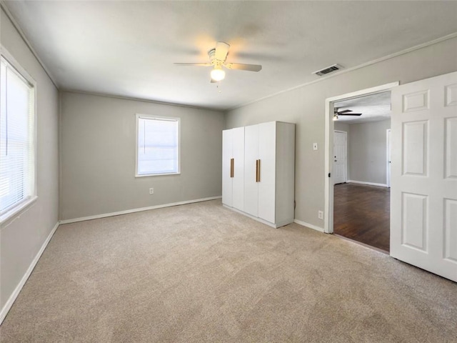 unfurnished bedroom with a ceiling fan, visible vents, light colored carpet, and baseboards