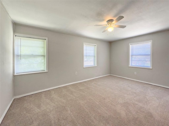 carpeted empty room with a ceiling fan and baseboards
